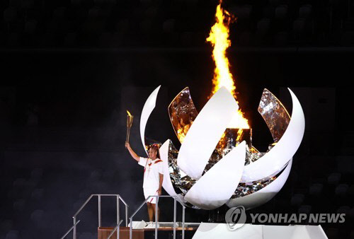 23일 일본 도쿄 신주쿠 국립경기장에서 열린 2020 도쿄올림픽 개막식에서 최종 성화 주자인 오사카 나오미가 성화대에 성화를 붙인 뒤 포즈를 취하고 있다.  연합뉴스
